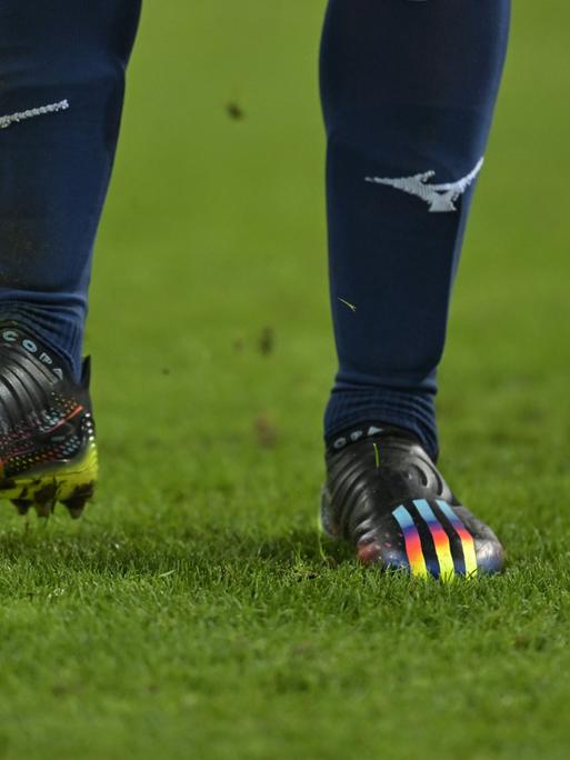 Szene aus dem Fußball-Bundesligaspiel FC Augsburg - VfL Bochum mit Regenbogenfarben auf dem Schuh eines Bochumer Spieler und auf dem Spielball

