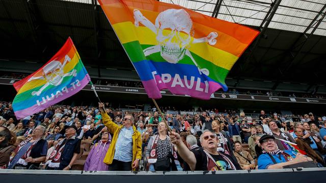 St. Pauli Fans schwingen Regenbogen Fahnen im Stadion.