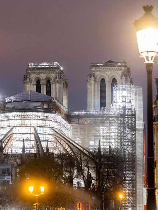 Eine Ansicht der nächtlich beleuchteten Kathedrale Notre Dame in Paris mit Baugerüsten