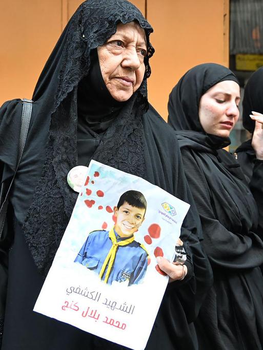 Angehörige trauern bei der Trauerfeier für Menschen, die im Libanon getötet wurden, als von Hisbollah-Mitgliedern benutzte Pager zur Explosion gebracht wurden. Eine Frau hält das Bild eines Kindes in der Hand. Libanon, 18. September 2024.