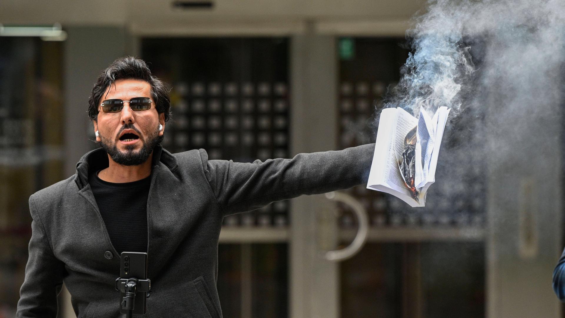 Der christliche Iraker Salwan Momika mit einem brennenden Koran in seiner Hand in Stockholm. 