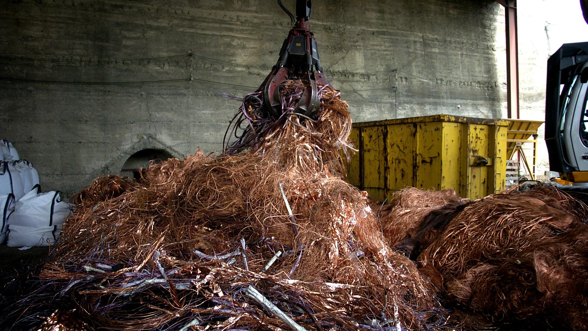 In einem Recyclingunternehmen werden Stromkabel mit einem Kran gehäuft.