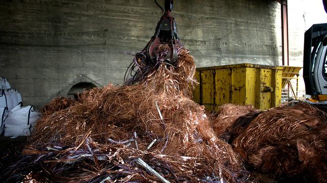 In einem Recyclingunternehmen werden Stromkabel mit einem Kran gehäuft.