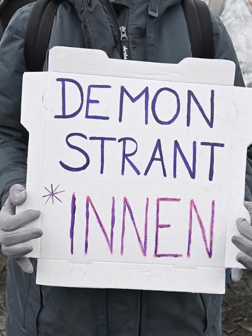 Demonstration gegen das Genderverbot in Bayern. Eine Person hält ein Schild mit der Aufschrift Demonstrant*innen.