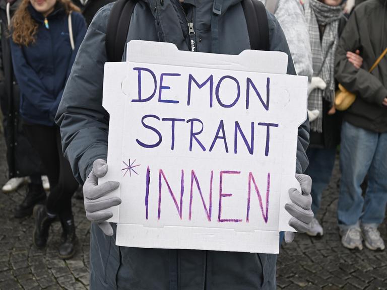 Demonstration gegen das Genderverbot in Bayern. Eine Person hält ein Schild mit der Aufschrift Demonstrant*innen.