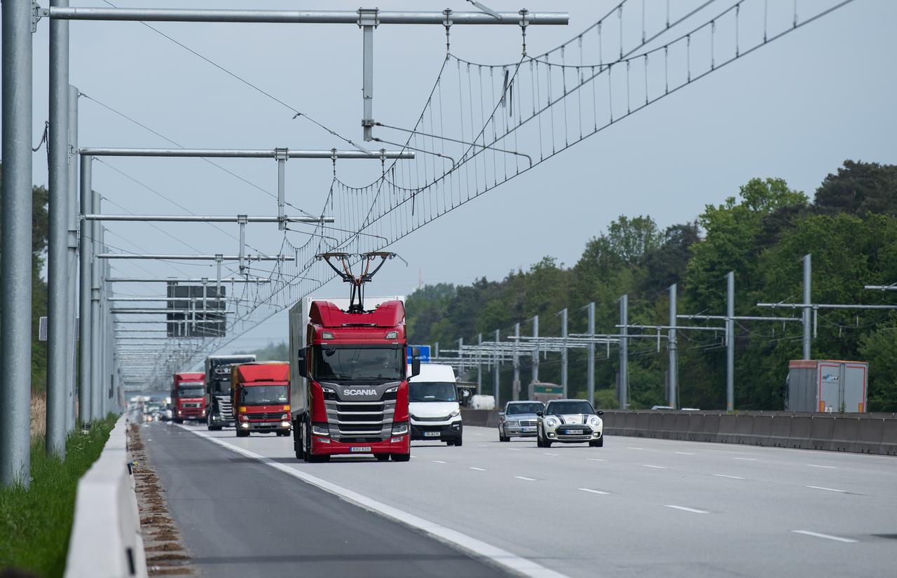 Eine Scania R450 Hybrid Zugmaschine (M) fährt mit ausgefahrenem Stromabnehmer während der Inbetriebnahme der ersten deutschen Teststrecke für E-Lastwagen mit Oberleitung auf der Autobahn 5 (A5).