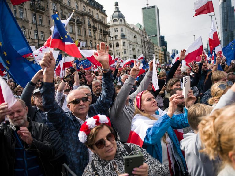 Demonstranten mit Fahnen und Blumenkränzen in Warschau