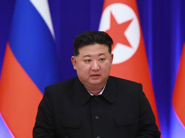 Porträt von Kim Jong Un mit der nordkoreanischen und der russischen Flagge im Hintergrund.