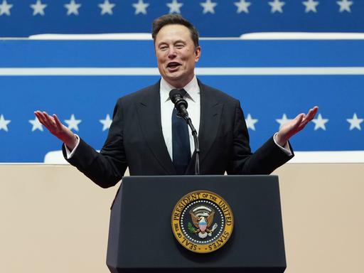 Tech-Milliardär Elon Musk spricht bei der Inaugurationsparade an einem Rednerpult mit dem Emblem des US-Präsidenten am 25. Januar 2025 in Washington.