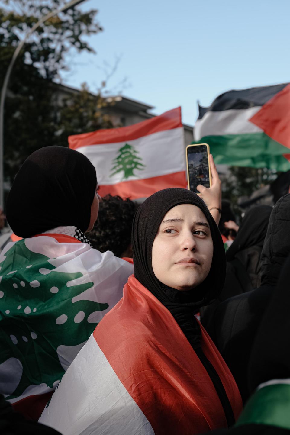 Eine Frau mit Kopftuch zeigt am 28. September 2024 während einer pro-palästinensischen und libanesischen Protestkundgebung in Berlin ihre Solidarität mit Libanon. Im Hintergrund sind palästinensische und libanesische Flaggen zu sehen.