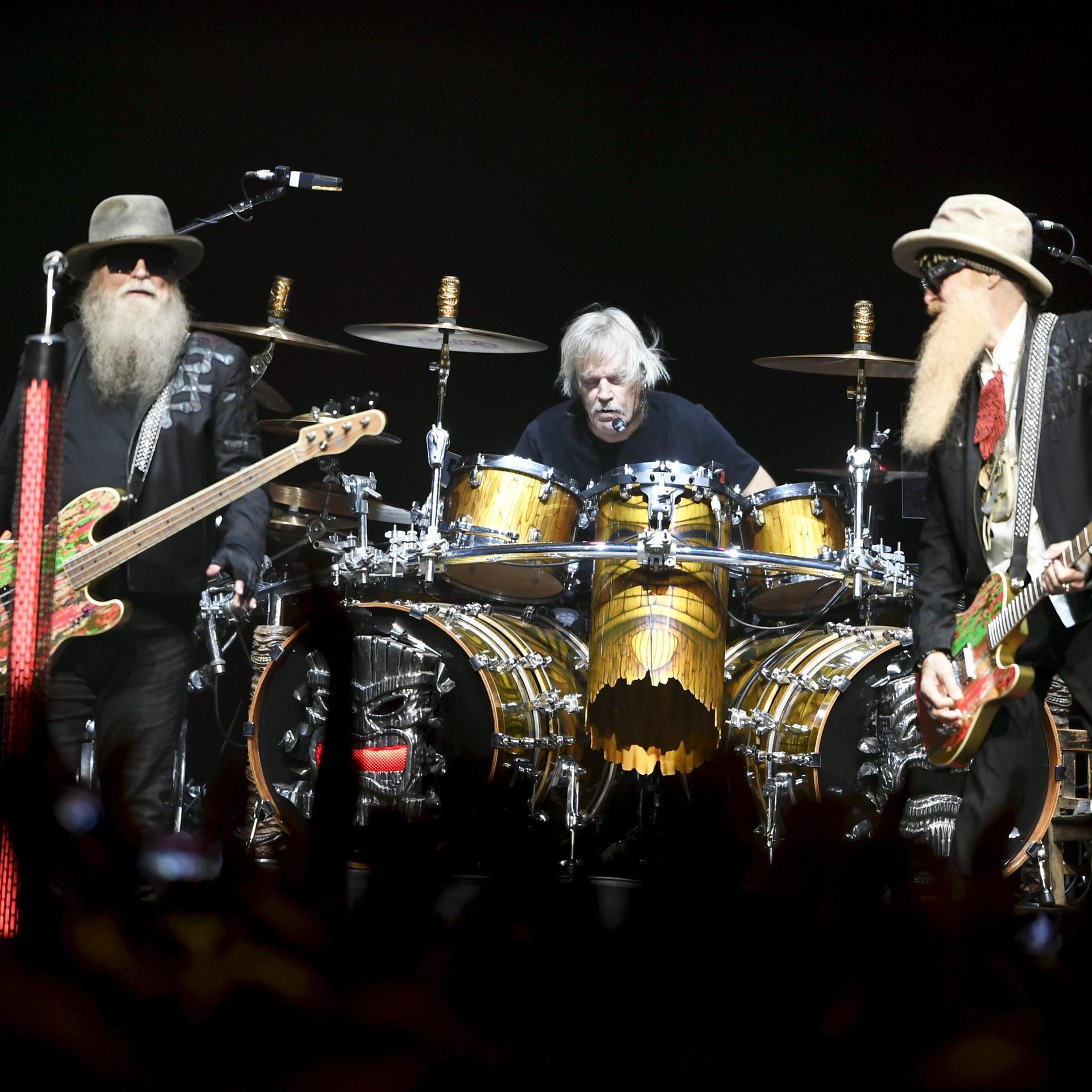 Die Band ZZ Top bei einem Auftritt in Helsinki: Rechts und links ein Mann mit langem Bart und einer E-Gitarre. In der Mitte sitzt ein dritter Mann an einem Schlagzeug, ohne Bart.