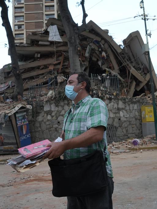 Ein Mann trägt Habseligkeiten aus einem eingestürzten Gebäude in Venezuelas Hauptstadt Caracas.