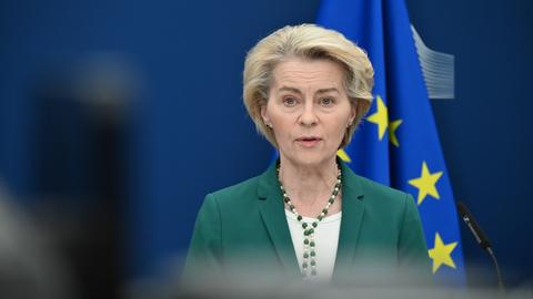 Von der Leyen hält eine Ansprache. Sie steht vor einer EU-Flagge, die teilweise zu sehen ist.  