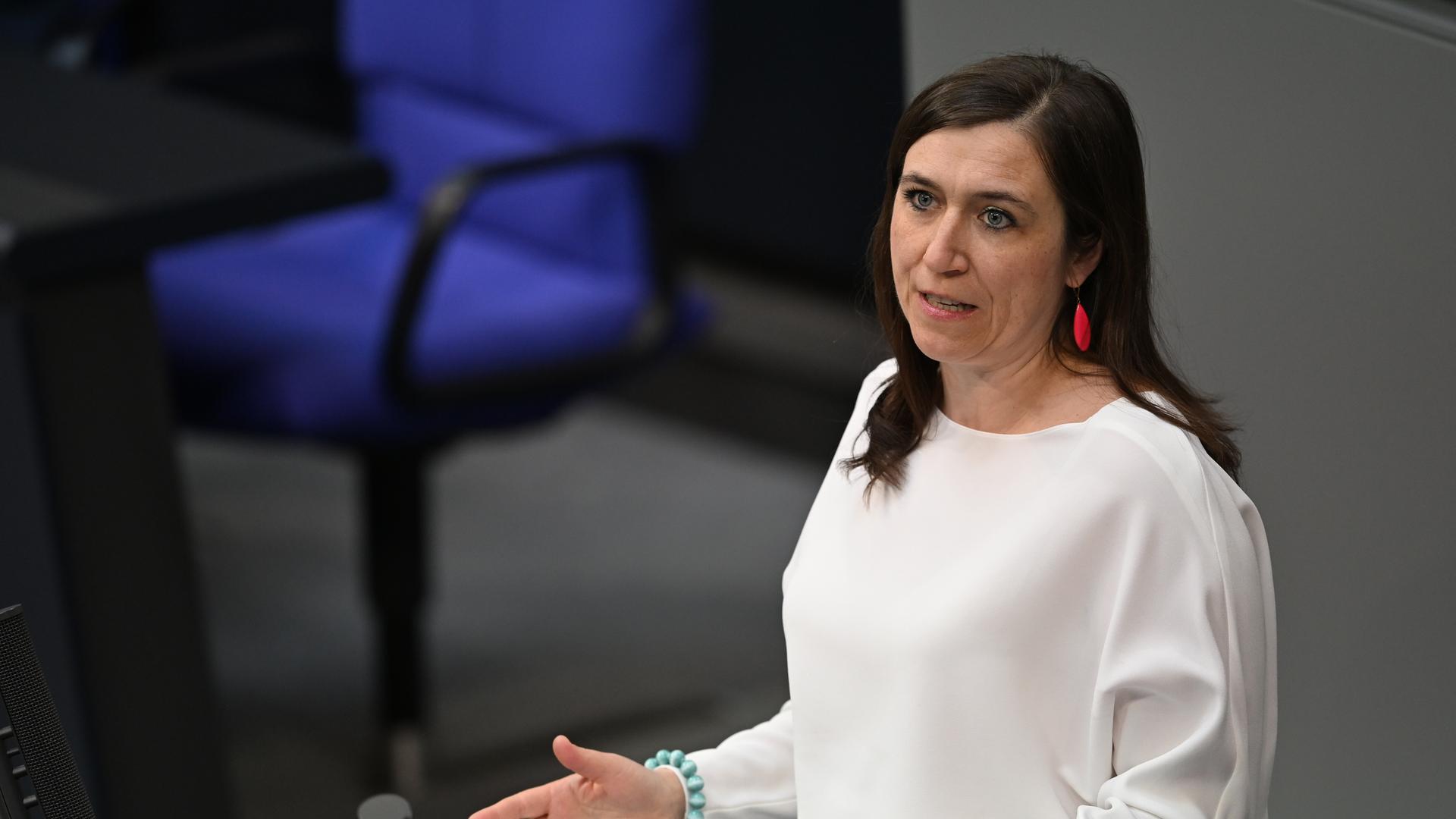 Katharina Beck steht an einem Rednerpult und spricht, sie trägt ein weißes Oberteil.