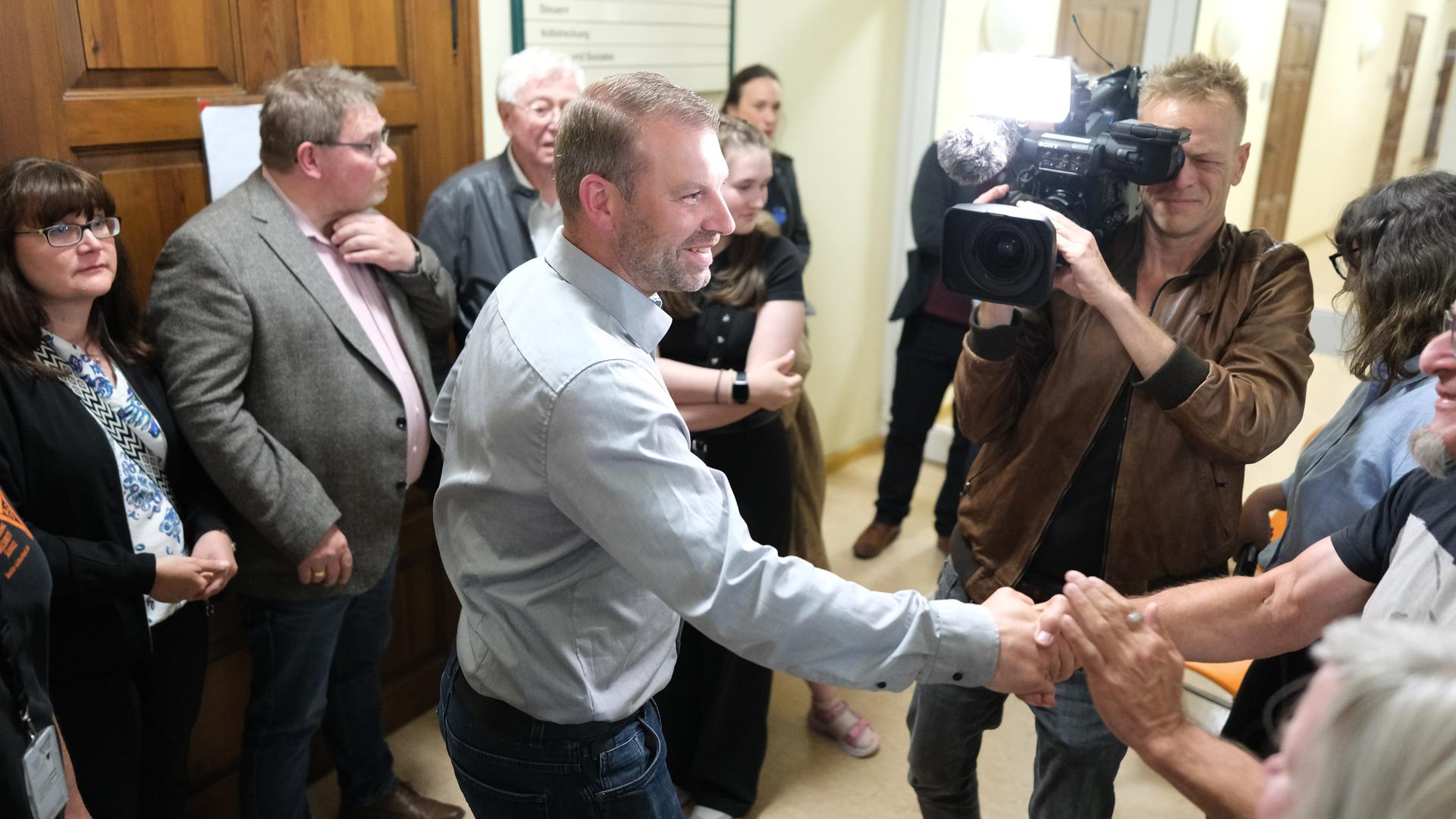 Marcus Hoffmann (CDU, M), Kandidat für das Amt des Oberbürgermeisters von Aue-Bad-Schlema, nimmt Glückwünsche entgegen. Er konnte sich im zweiten Wahlgang gegen den Kandidaten der Freien Sachsen durchsetzen. Marcus Hoffmann (CDU, M), Kandidat für das Amt des Oberbürgermeisters von Aue-Bad-Schlema, nimmt Glückwünsche entgegen. Er konnte sich im zweiten Wahlgang gegen den Kandidaten der Freien Sachsen durchsetzen.
