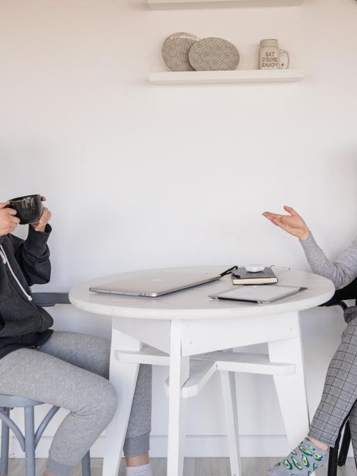 Zwei Frauen sitzen an einem Tisch und unterhalten sich. 