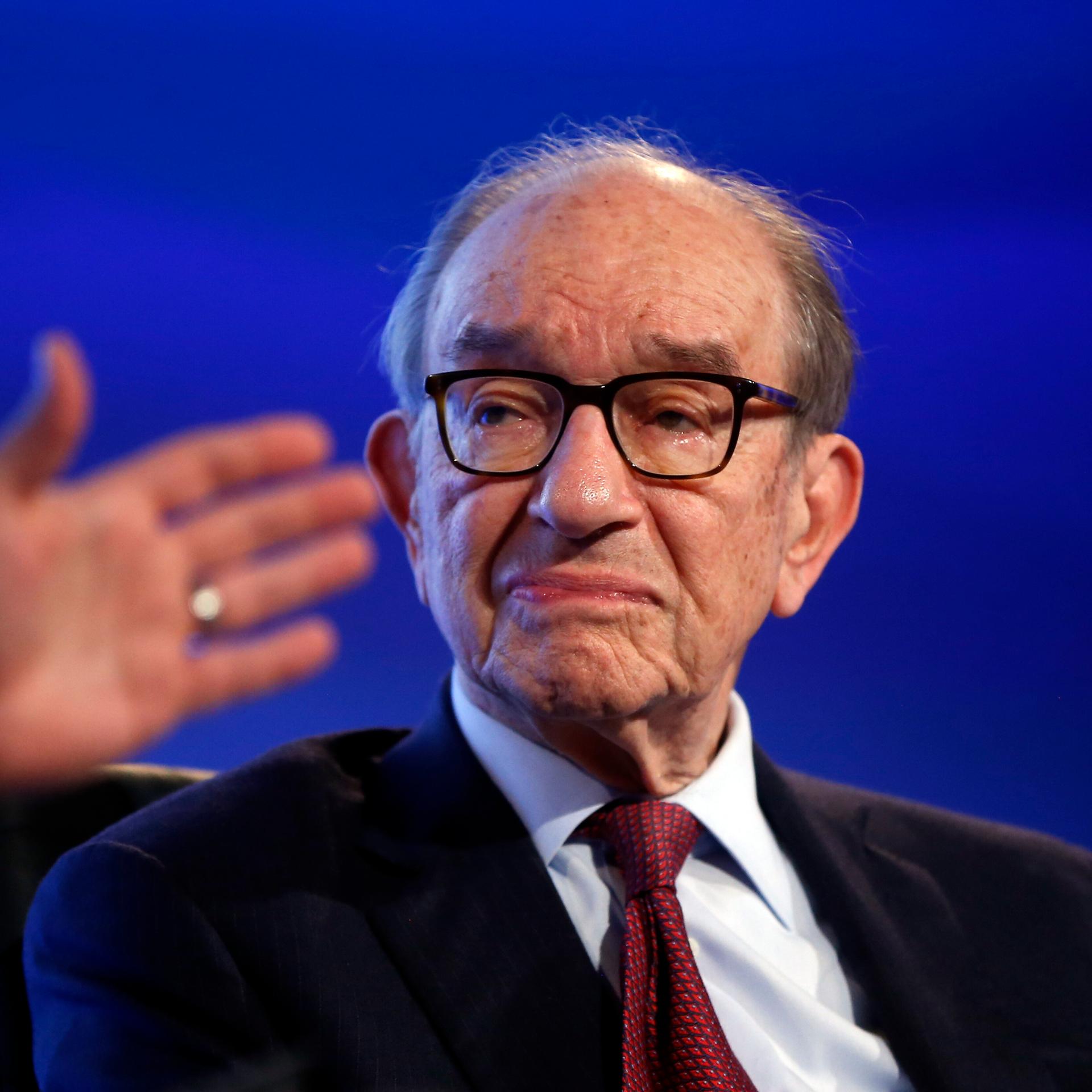 Alan Greenspan im Porträt, rechts von ihm sieht man verschwommen die Hand seines Gesprächspartners.