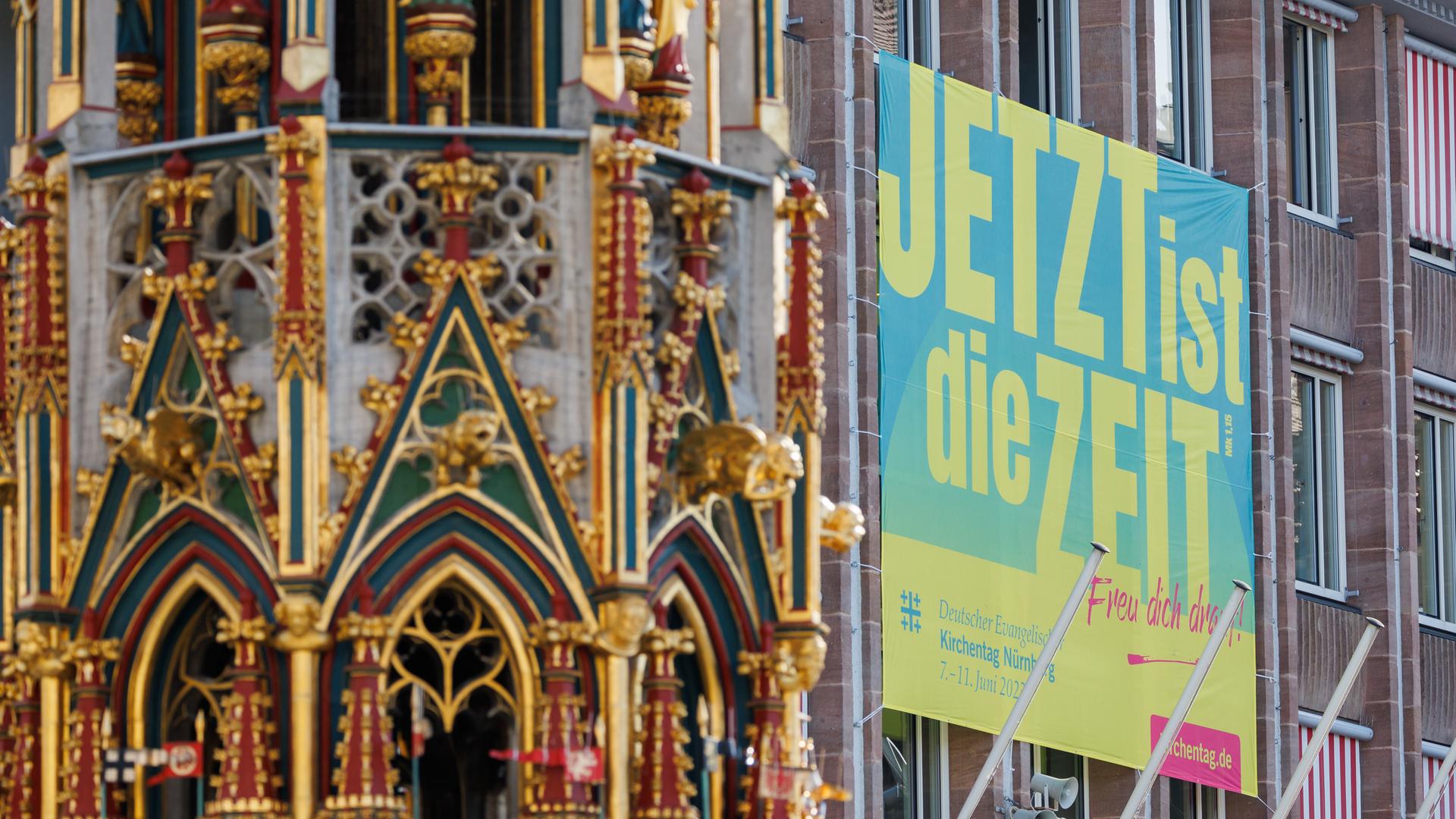 Ein Plakat zum Evangelischen Kirchentag mit dem Slogan "Jetzt ist die Zeit" hängt an der Außenfassade des Rathauses am Hauptmarkt in Nürnberg.