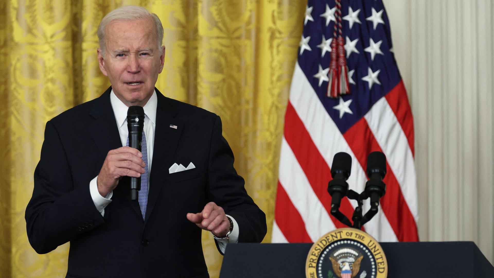 US-Präsident Joe Biden im Weißen Haus. Er steht vor einem Rednerpult und der amerikanischen Flagge und hält ein Mikrofon in der Hand.
