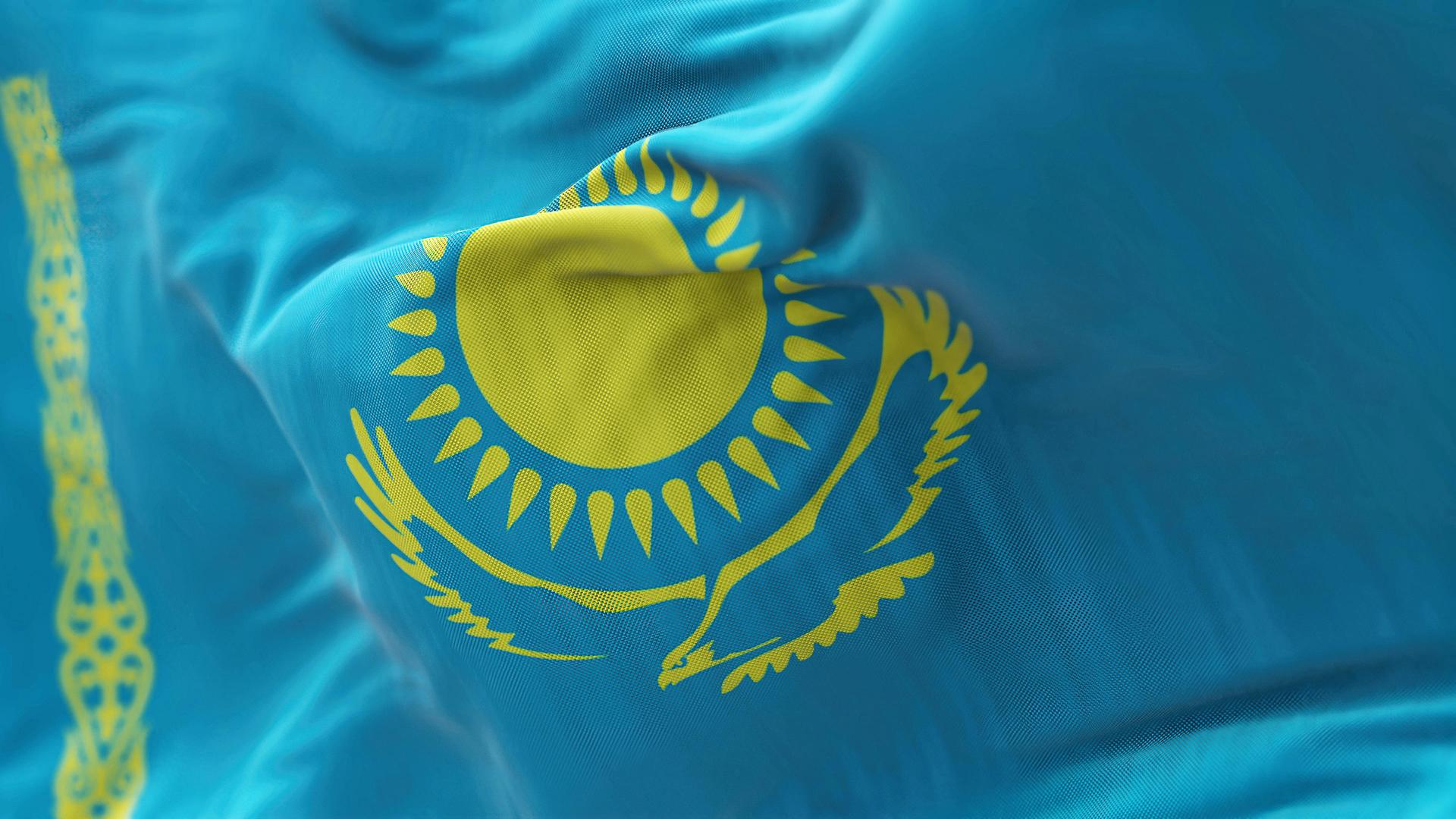 Großaufnahme der Flagge von Kaschstan: Ein goldgelbes Muster auf hellblauem Grund.