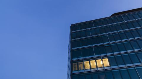 Nächtliches Bürogebäude mit einigen hellen Fenstern.
