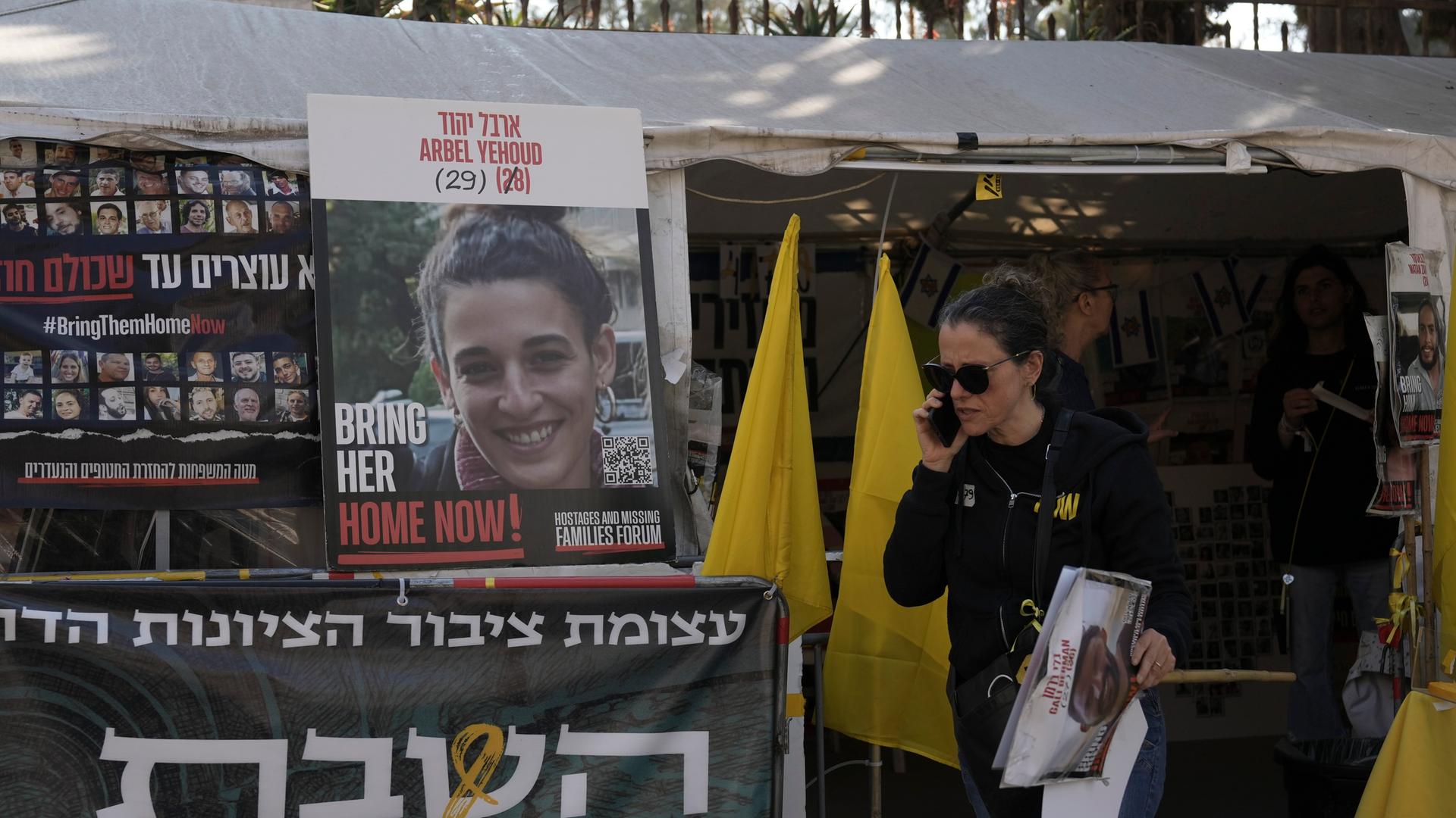 Jerusalem: Eine Frau geht am Eingang eines Zeltes in Jerusalem an einem Foto von Arbel Yehud und einem hebräischen Transparent vorbei, auf dem die Rückkehr der von der Hamas im Gazastreifen festgehaltenen Geiseln gefordert wird.