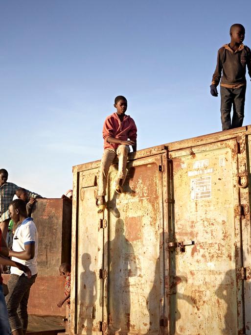 Junge Menschen aus Mali stehen auf einem Container am Niger in Segou.
