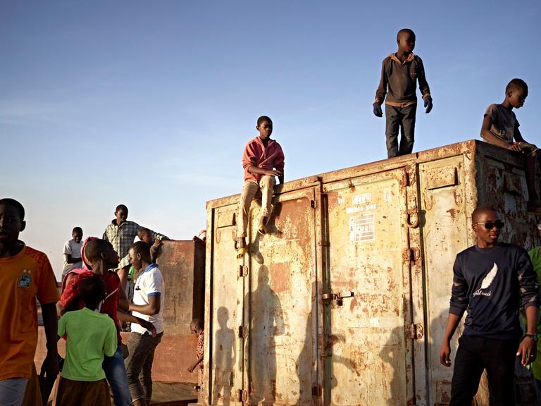 Junge Menschen aus Mali stehen auf einem Container am Niger in Segou.
