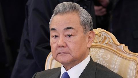 Der chinesische Außenminister Wang Yi sitzt auf einem Stuhl und schaut ernst.