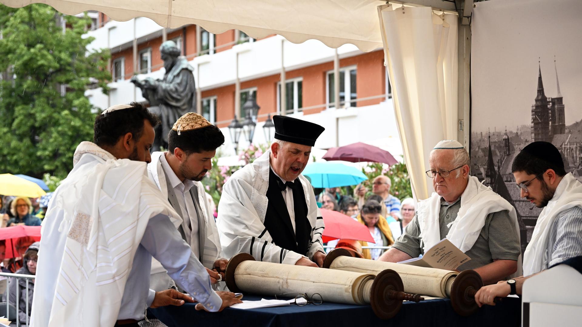 Das Foto zeigt jüdische Geistliche bei der Feier eines Gottesdienstes. Auf einem Tisch liegt eine Torarolle. Das Foto zeigt jüdische Geistliche bei der Feier eines Gottesdienstes. Auf einem Tisch liegt eine Torarolle.