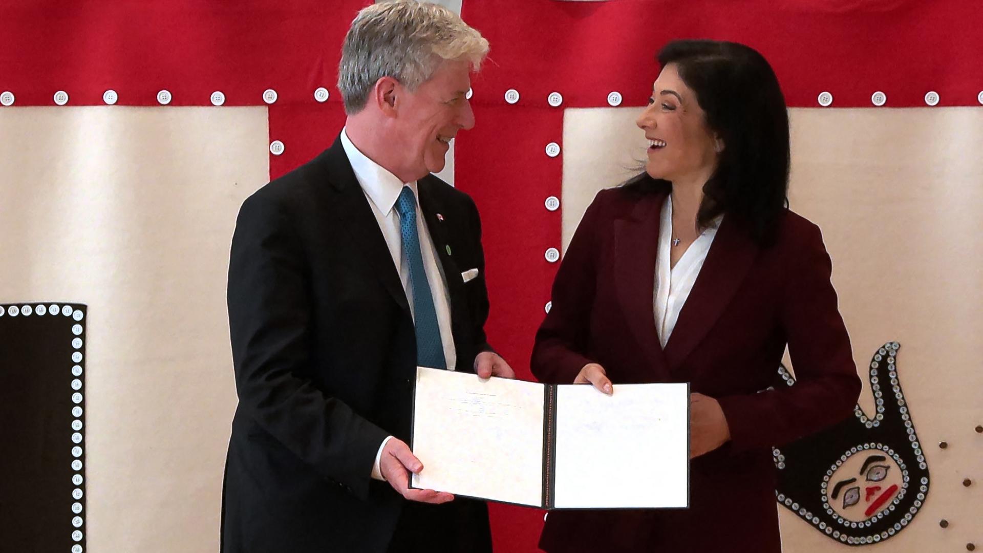 Bundeswirtschaftsministerin Reiche und der kanadische Energieminister Hodgson halten gemeinsam ein Schriftstück fest und lachen sich an.