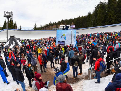 Zuschauerinnen und Zuschauer stehen in einem Kreisel an der Rodelbahn in Altenberg.