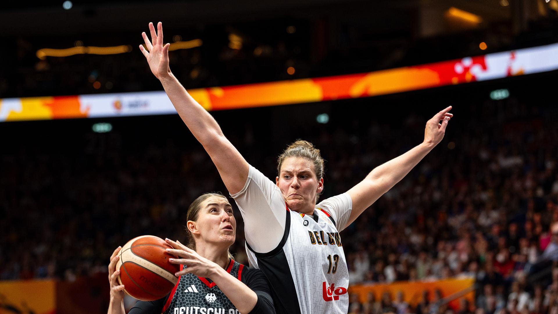 Die deutsche Basketballerin Luisa Geiselsoder in einem schwarzen Trikot setzt zum Korbleger an. Kyara Linskens aus Belgien in Weiß versucht zu blocken.