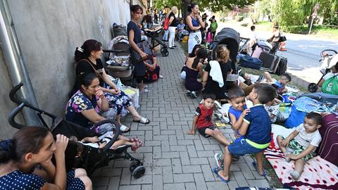 Ukrainische Flüchtlinge sitzen auf einem Bürgersteig.
