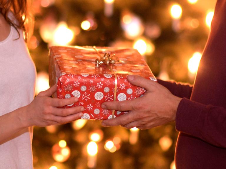 Zwei Menschen beschenken sich an Heilig Abend. Mann und Frau tauschen ein Geschenk aus