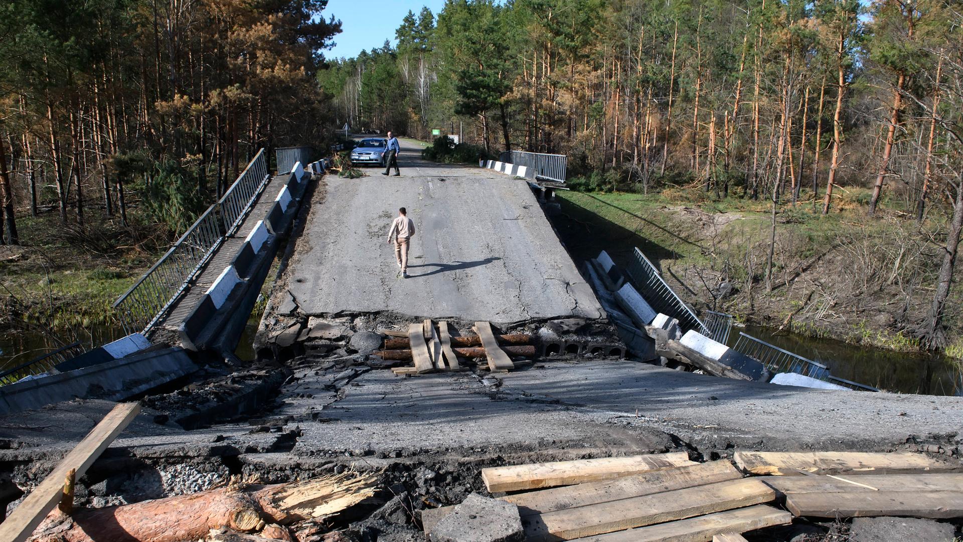 Ein Mann geht im Norden von Kiew auf einer völlig zerstörten Brücke entlang. Ein Mann geht im Norden von Kiew auf einer völlig zerstörten Brücke entlang.