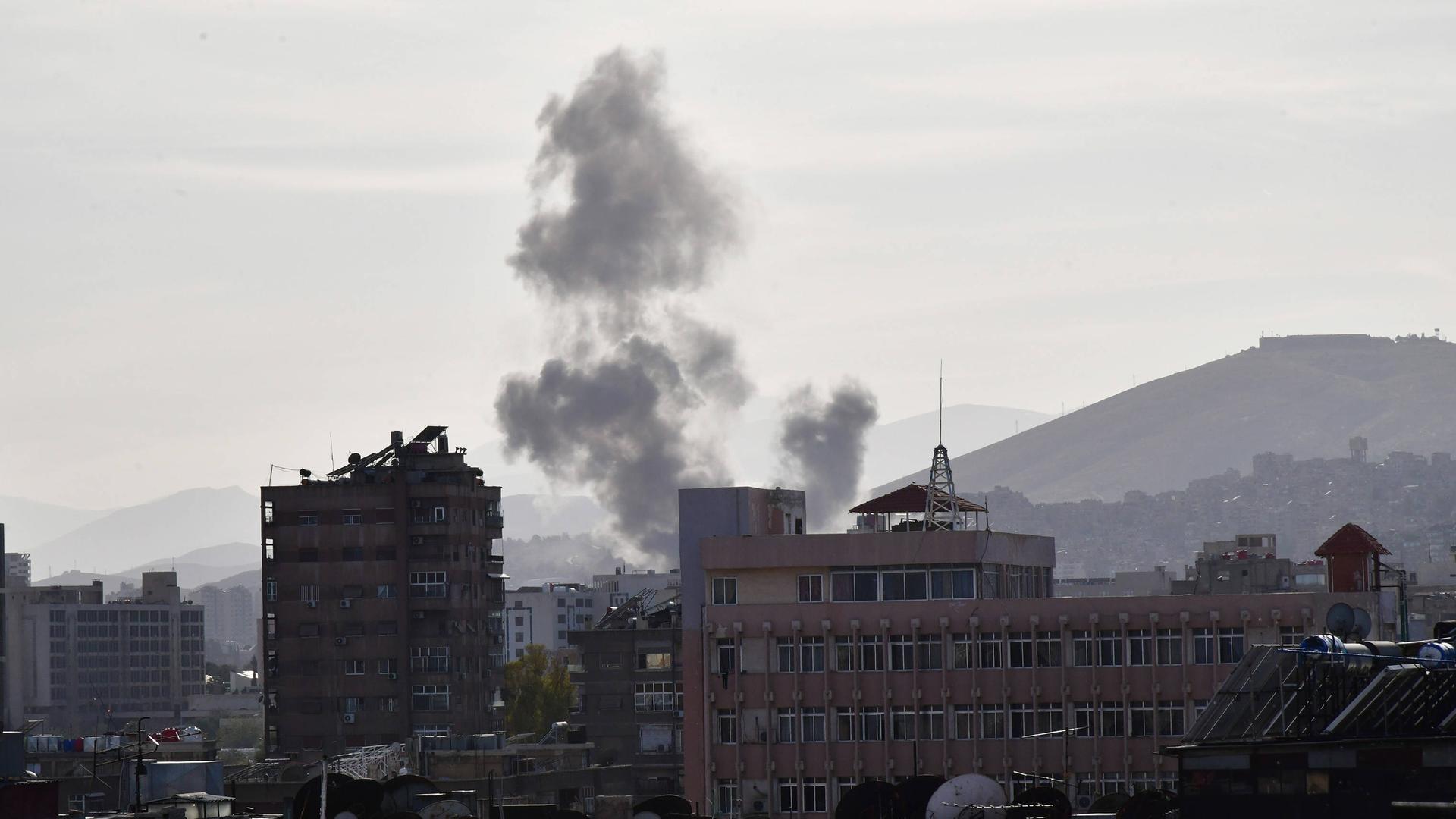 Eine Rauchfahne steigt über Gebäuden nach einem Raketenangriff in Damaskus auf.