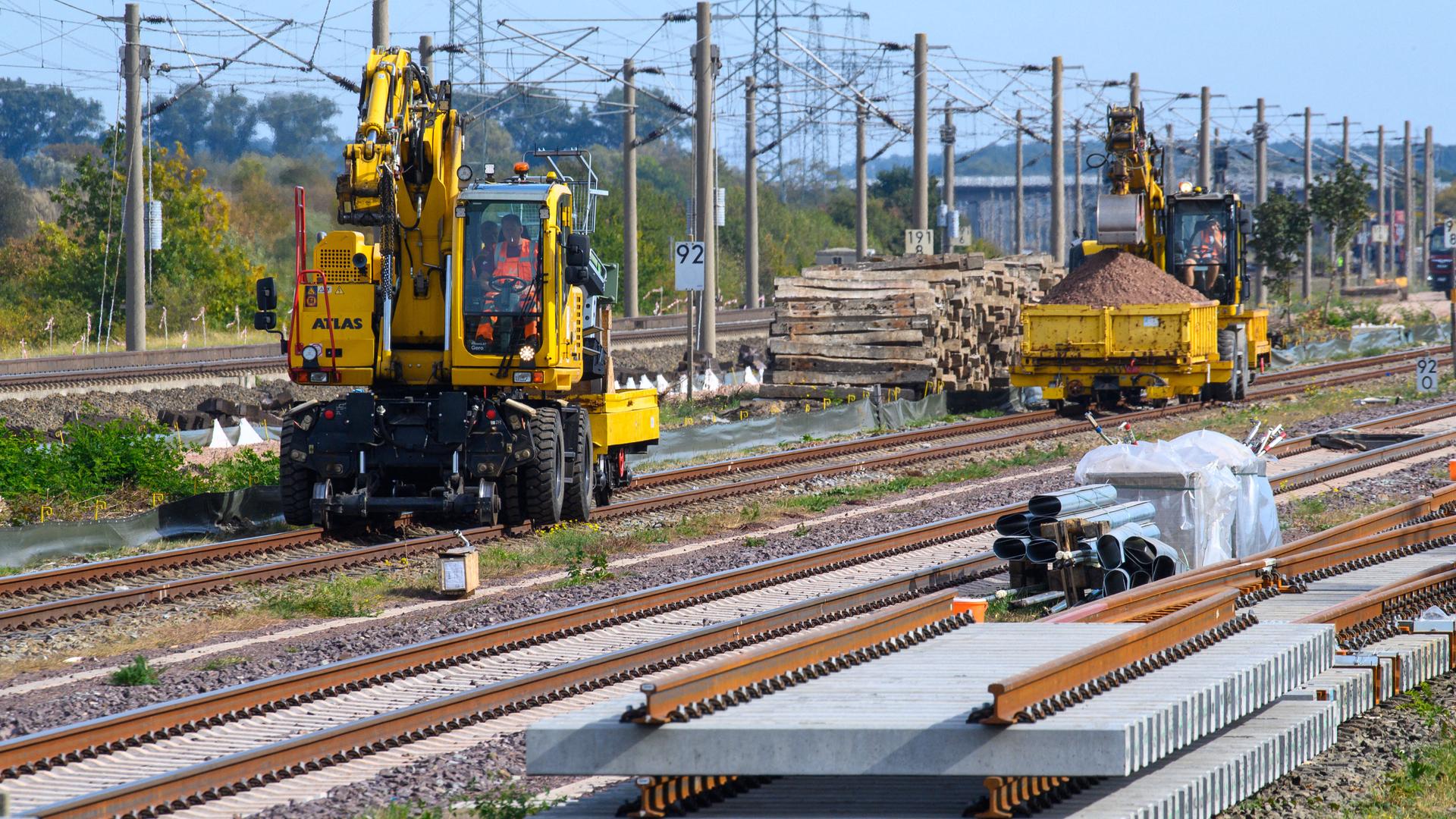 Das Bild zeigt ein Gleisbaufahrzeug. Im Vordergrund sind Gleisteile zu sehen.