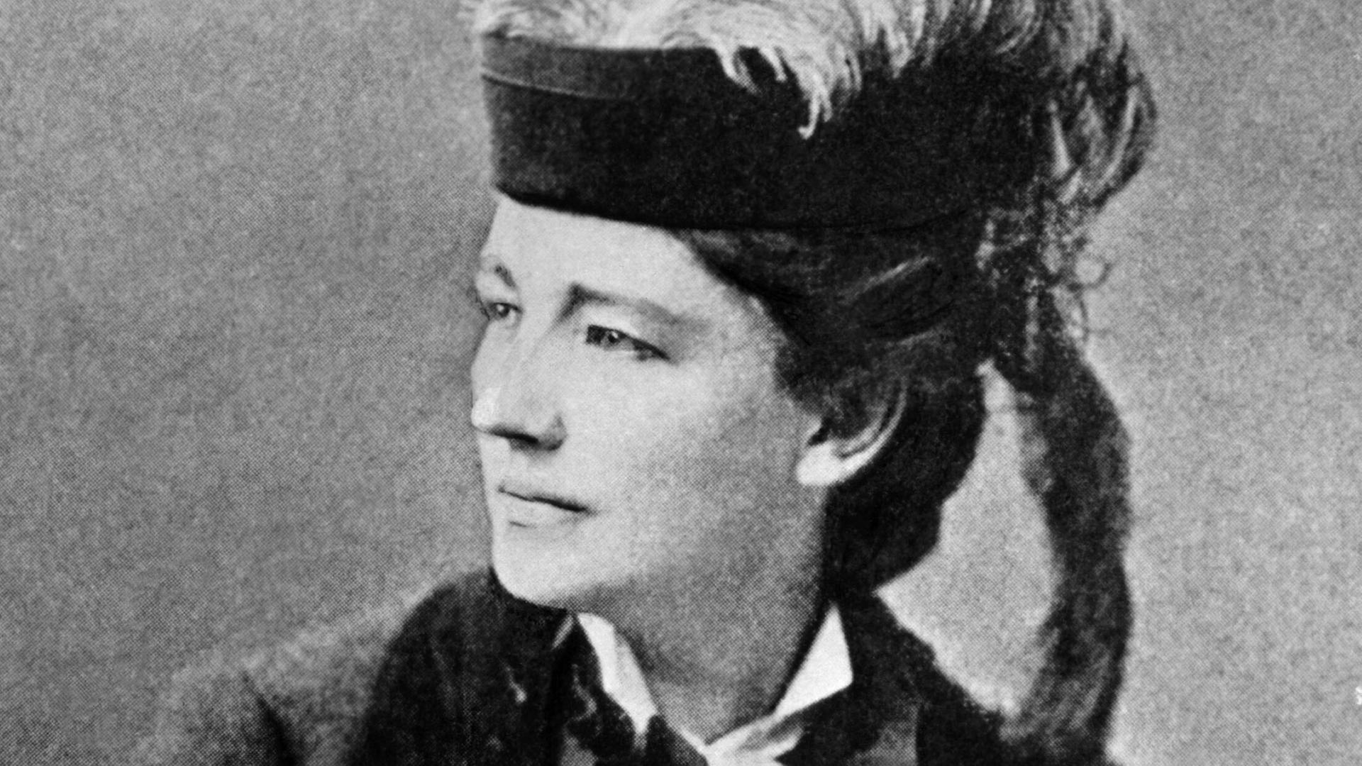 Schwarzweiß-Fotografie von Victoria Woodhull um 1890 - sie trägt einen Pferdeschwanz und einen Hut mit Feder