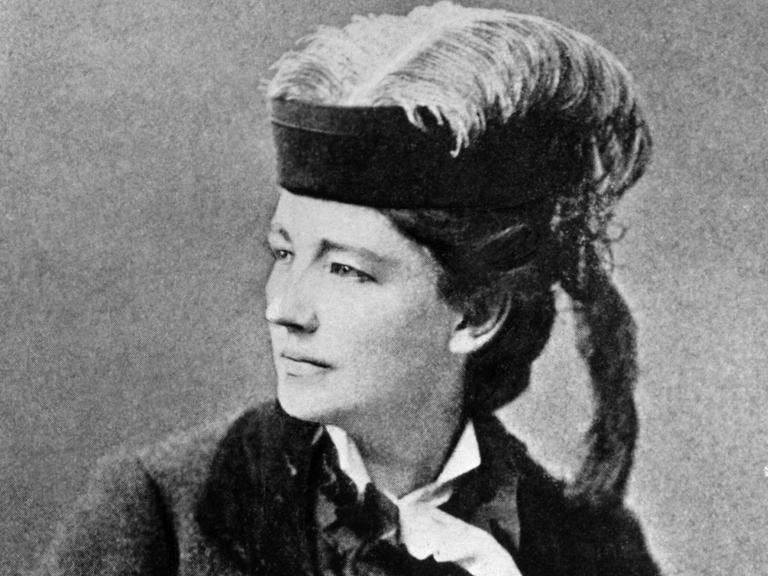 Schwarzweiß-Fotografie von Victoria Woodhull um 1890 - sie trägt einen Pferdeschwanz und einen Hut mit Feder