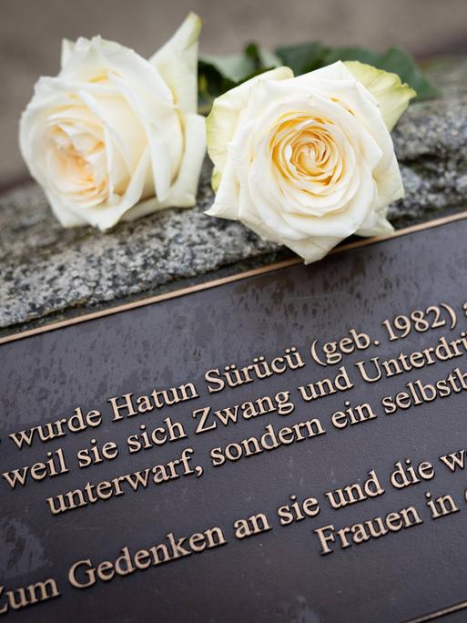 Zwei weiße Rose liegen auf einem Gedenkstein, der am Tatort in der Oberlandstrasse in Tempelhof-Berlin an Hatün Sürücü erinnert.