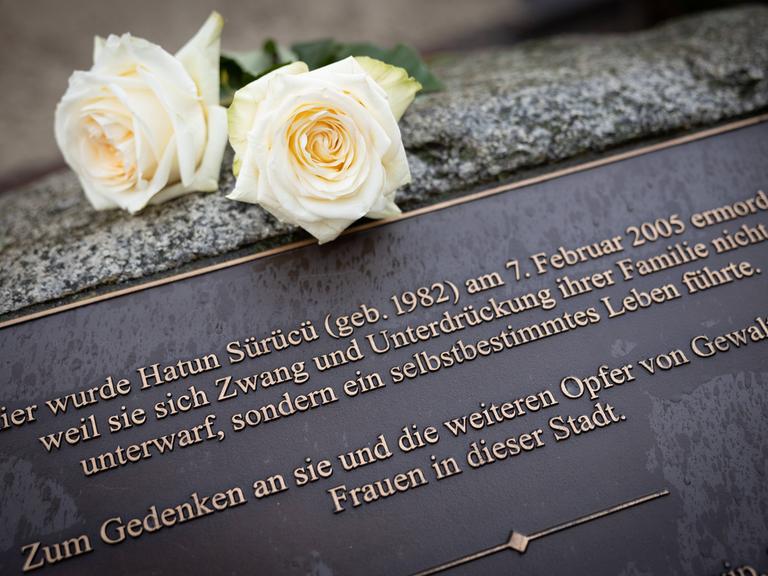 Zwei weiße Rose liegen auf einem Gedenkstein, der am Tatort in der Oberlandstrasse in Tempelhof-Berlin an Hatün Sürücü erinnert.