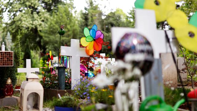 Mit bunten Windspielen und Figuren dekorierte Kindergräber.