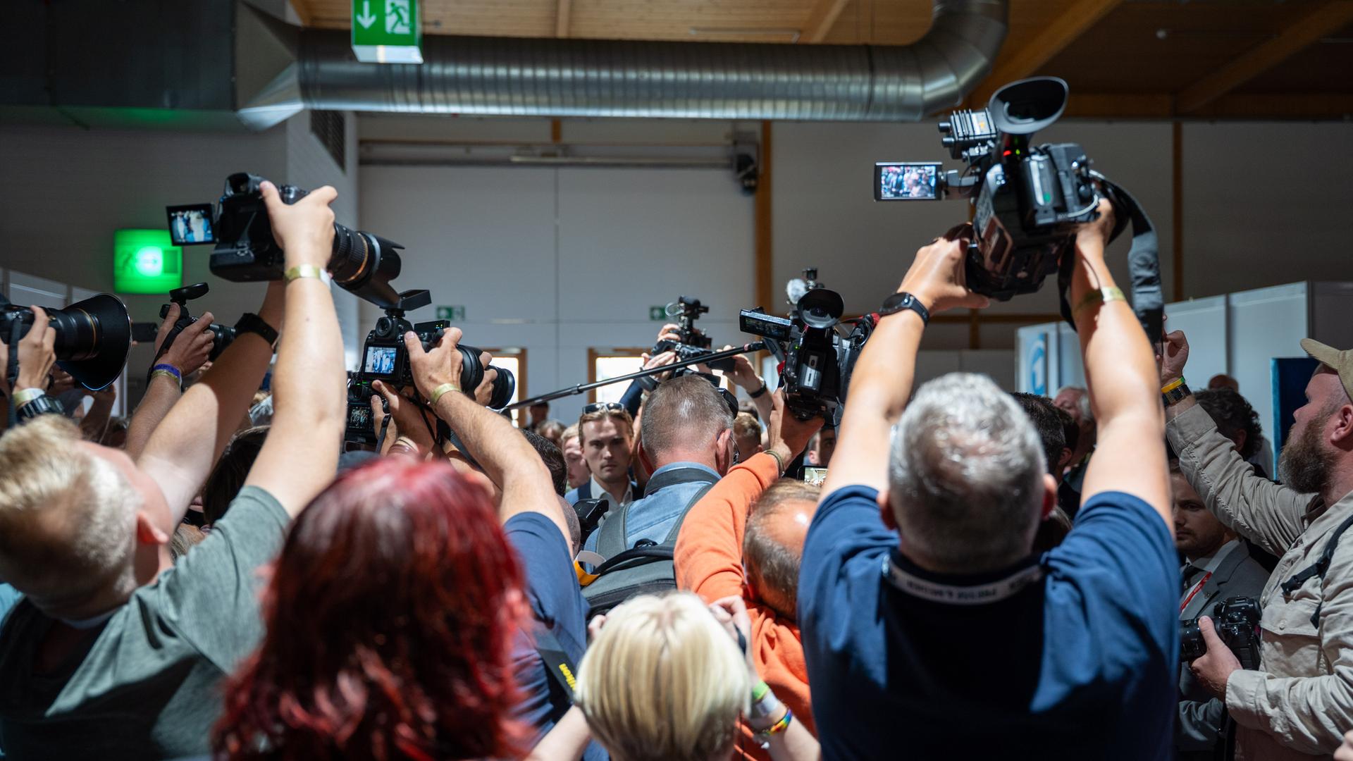 Zahlreiche Journalistinnen und Journalisten stehen mit dem Rücken zur Kamera. Sie halten eigene Kameras und Mikrofone in die Höhe. Zahlreiche Journalistinnen und Journalisten stehen mit dem Rücken zur Kamera. Sie halten eigene Kameras und Mikrofone in die Höhe.