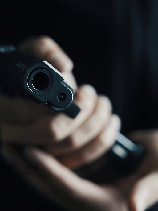 Eine Hand hält eine Pistole in die Kamera
