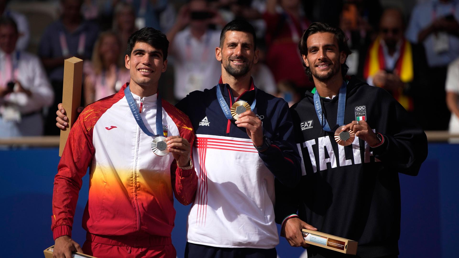 Novak Djokovic, Carlos Alcaraz und Lorenzo Musetti stehen lachend nebeneinander. Novak Djokovic, Carlos Alcaraz und Lorenzo Musetti stehen lachend nebeneinander.