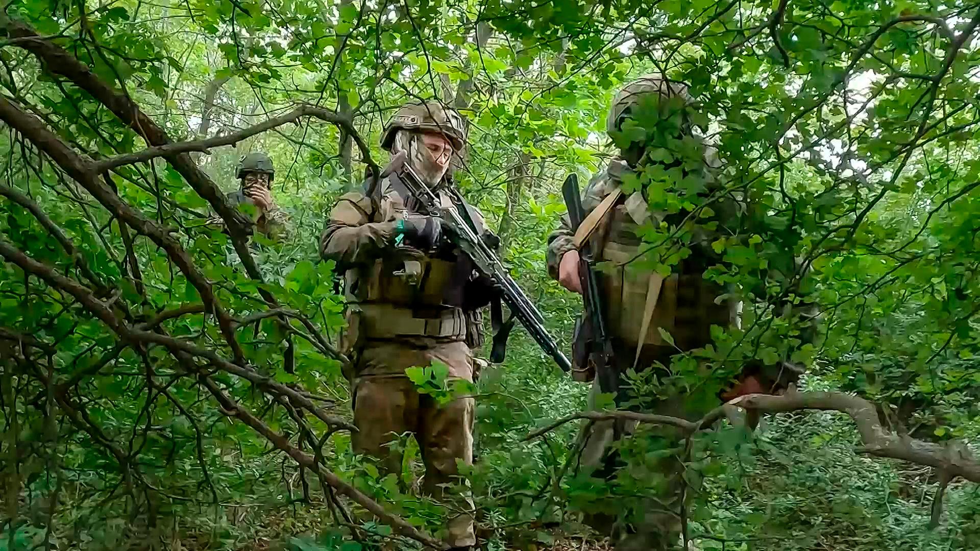 Russische Soldaten laufen durch ein Waldgebiet.