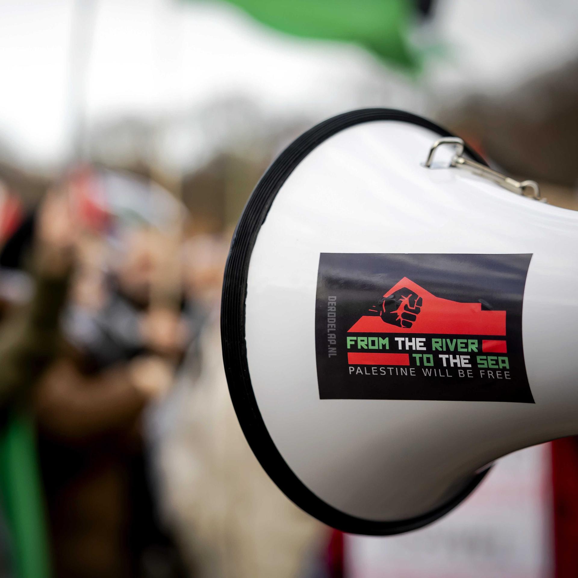 Während einer Pro-Palästina-Demonstration wird ein Megaphon mit der Aufschrift "Vom Fluss bis zum Meer" hoch gehalten. Die Parole gilt als antisemitisch, weil sie das Existenzrecht Israels in Frage stellt. 