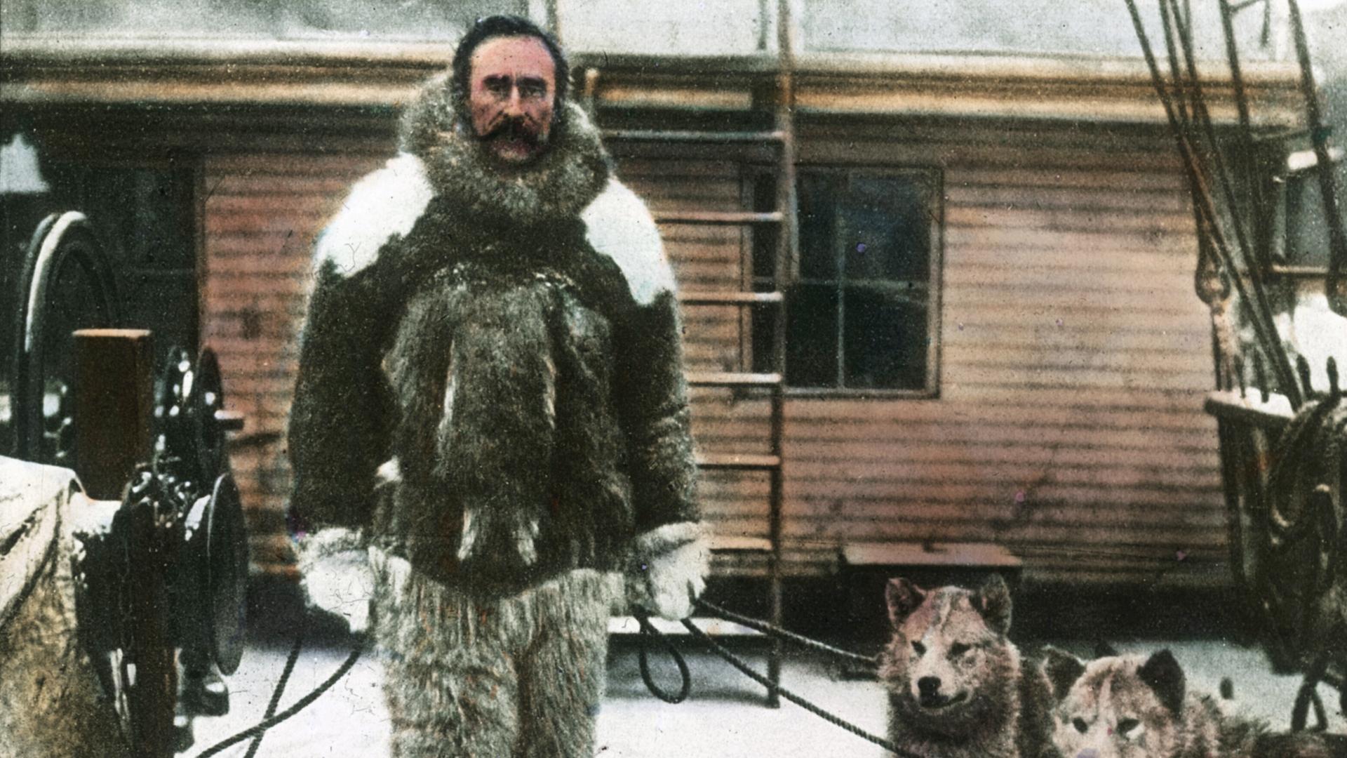 Eine kolorierte historische Fotografie des Polarforschers Robert Ewin Peary, der behauptete, 1909 den Nordpol entdeckt zu haben. Er trägt dicke Fellkleidung und hält mehrere Polarhunde an der Leine.