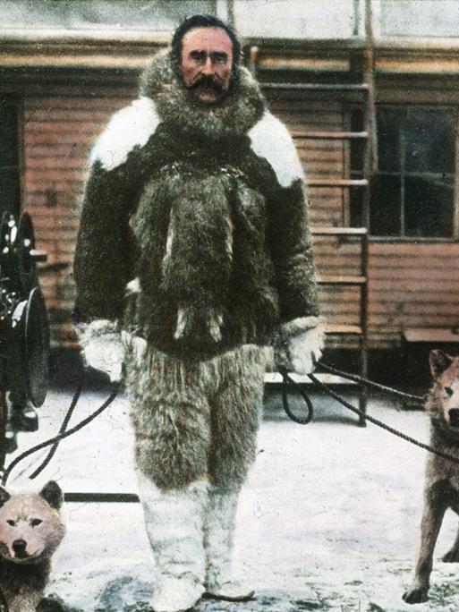 Eine kolorierte historische Fotografie des Polarforschers Robert Ewin Peary, der behauptete, 1909 den Nordpol entdeckt zu haben. Er trägt dicke Fellkleidung und hält mehrere Polarhunde an der Leine.